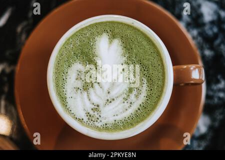 Piatto Lay o vista dall'alto shot di una tazza di latte Matcha con bella latte Art su tavolo in marmo nero Foto Stock