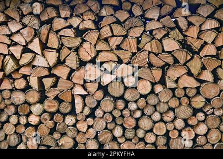 Una pila di tronchi appena tagliati disposti ordinatamente su uno sfondo rustico di legno Foto Stock