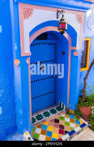 Porta d'ingresso blu, pavimento d'ingresso decorato con piastrelle a mosaico di diversi colori Foto Stock