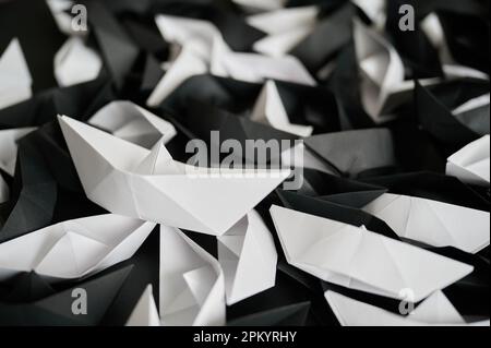 Cumulo con molte navi di origami di carta in bianco e nero disposte su una superficie scura Foto Stock