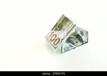 Forma della casa fatta da 100 dollari Bills su sfondo bianco Foto Stock