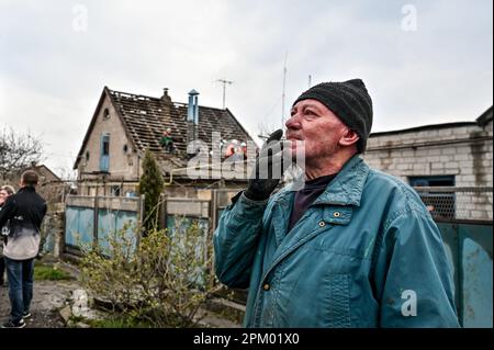 ZAPORIZHZHZHIA, UCRAINA - 9 APRILE 2023 - Un uomo fuma una sigaretta sul luogo dello sciopero del razzo dell'esercito russo sul settore residenziale, Foto Stock