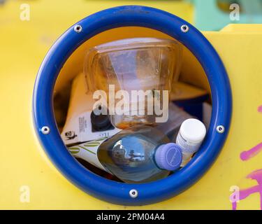 Una raccolta di bottiglie in un cestino giallo - rifiuti, riciclaggio Foto Stock