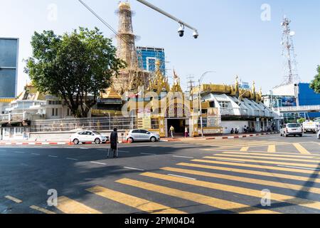 Yangon, Myanmar. 10th Apr, 2023. Qualcuno attraversa un incrocio di fronte alla Pagoda di Sule a Yangon. Il 1 febbraio 2021, il governo della giunta militare (Tatmadaw) ha preso il potere con il colpo di stato, incarcerando il governo della NLD (Lega Nazionale per la democrazia) democraticamente eletto e gettando il paese in una crisi umanitaria in corso, descritta da molti come una guerra civile o l'rivolta popolare. Credit: SOPA Images Limited/Alamy Live News Foto Stock