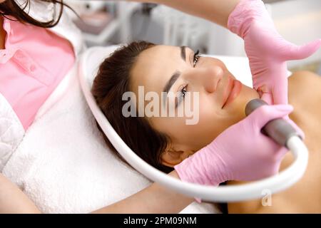 Procedura viso cosmetica, trattamento viso. Cosmetologist sta effettuando un trattamento facciale su una giovane donna, ringiovanimento dell'acqua, servizio di Cosmetologia, servizio dermatologico Foto Stock