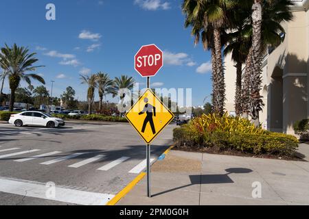 Un segnale di stop con un cartello di passaggio pedonale all'esterno di un centro commerciale è mostrato a Orlando, Florida, Stati Uniti. Foto Stock