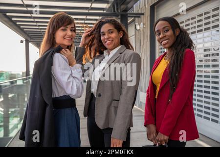 Tre colleghi sorridenti lasciano gli uffici alla fine della giornata lavorativa Foto Stock
