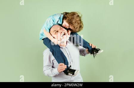 Nonno porta il nipote sulle spalle su sfondo verde isolato. Generazione maschile, Foto Stock