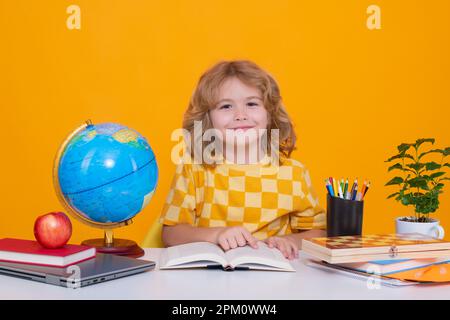 Ritorno a scuola. Divertente ragazzino della scuola elementare con un libro. Ritratto di scolaro isolato su sfondo giallo studio. Istruzione. Foto Stock