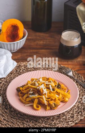 Fettuccine Pasta con zucca e salsa alla panna acida con funghi guarniti con parmigiano grattugiato Foto Stock