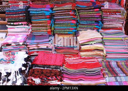 Pila di sciarpe pashmina per la vendita in un negozio di moda Foto Stock