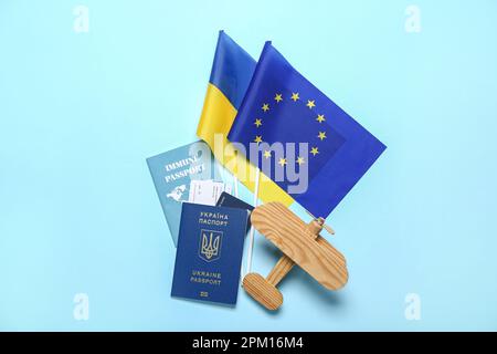 Passaporti con velivolo giocattolo, bandiere dell'Ucraina e dell'Unione europea su sfondo blu Foto Stock