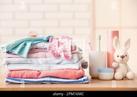 Stack di diversi vestiti per bambini, cosmetici e accessori sul tavolo in camera, primo piano Foto Stock