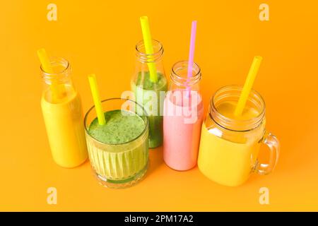 Bicchieri e bottiglie di frullato colorato su sfondo colorato Foto Stock