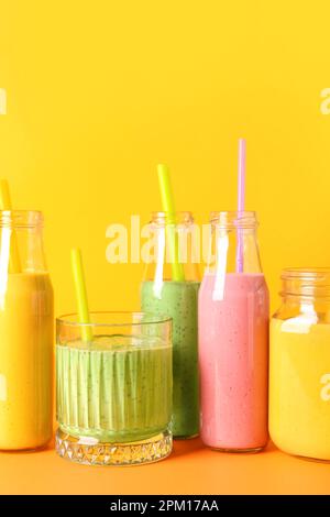 Bicchieri e bottiglie di frullato colorato su sfondo colorato Foto Stock