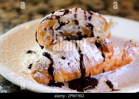 Cioccolato versato su croissant primo piano. Cioccolato con un croissant su un piatto. Riprese FullHD di alta qualità Foto Stock