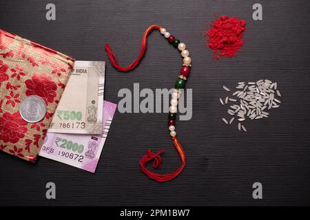 Rakhi con valuta indiana e roli Chawal su sfondo testurizzato Foto Stock