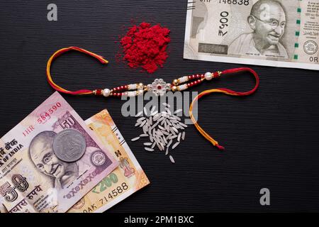 Vista dall'alto di rakhi con soldi indiani e roli Chawal Foto Stock