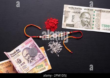 Vista dall'alto di rakhi con soldi indiani e kumkum Foto Stock