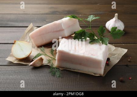 Gustoso maiale salato con erbe, cipolla e aglio su tavola di legno Foto Stock