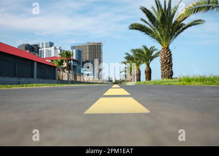 Pista ciclabile con linee di demarcazione gialle dipinte su asfalto, primo piano Foto Stock