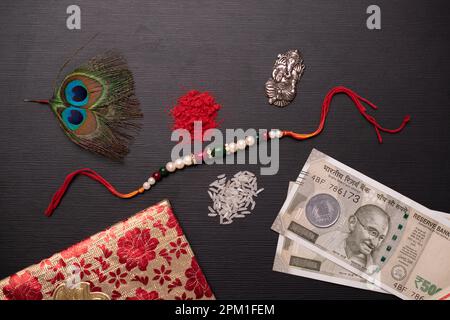 Vista dall'alto di rakhi con roli Chawal e soldi, concetto di raksha bandhan Foto Stock