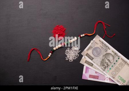 Vista dall'alto di perline rakhi con roli e valuta indiana Foto Stock