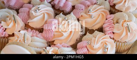Cupcake con perle di zucchero d'argento, cupcake alla vaniglia con crema rosa, bianca e pesca, fuoco selettivo, primo piano Foto Stock