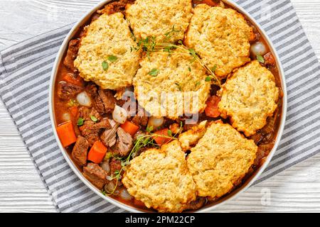 costolette di manzo disossate stufate con gnocchi, carote, cipolle di timo e perla in un recipiente bianco su un tavolo di legno bianco, piatto, primo piano Foto Stock