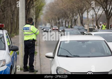 Bucarest, Romania - 8 aprile 2023: L'ufficiale della polizia stradale rumena utilizza un radar ad alta velocità su una strada a Bucarest Foto Stock