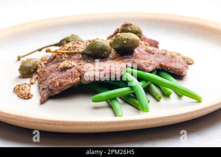 bistecca di maiale con salsa di senape e capperi serviti con fagiolini verdi Foto Stock