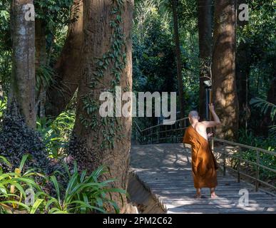 Un giovane monaco buddista che scava i gradini in pietra fino al tempio. Chiang mai, Thailandia. Foto Stock