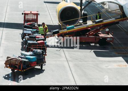 Bilbao, Spagna - 9 aprile 2023: I lavoratori che appoggiano bagagli in un rimorchio per caricare un aereo all'aeroporto di Bilbao Foto Stock