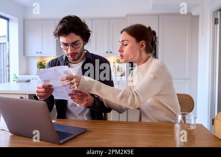 Coppia preoccupata a casa che guarda la bolletta energetica del laptop Holding Foto Stock
