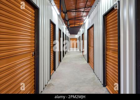 Corridoio dell'unità di self-storage con porte rosse. Unità di stoccaggio a noleggio Foto Stock