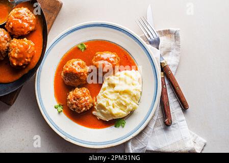 Polpette fritte brasate in salsa di pomodoro servite con purè di patate su un tavolo bianco. Mangiare polpette arrosto di manzo in salsa di pomodoro. Foto Stock