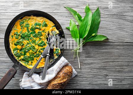 Frittata primaverile con ramson fresco o foglie di aglio selvatico. Dieta sana di primavera concetto di cibo. Foto Stock