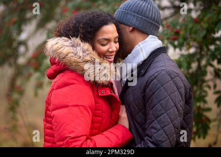 Coppia che indossa cappotti e sciarpe a piedi nella campagna autunnale Misty Foto Stock