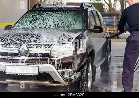 Kaliningrad, Russia, 1 marzo 2020. Un uomo lava la sua auto con un autolavaggio senza contatto. Lavando la sua auto Renault marrone. Il SUV al lavaggio auto. Foto Stock