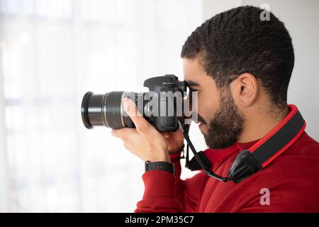 Vista laterale del giovane uomo barbuto fotografo che scatta foto Foto Stock
