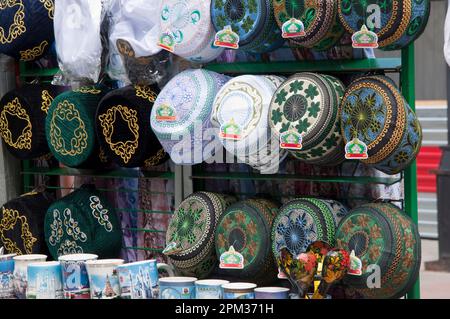 Un tradizionale decorato cappelli, cappelli e headware maschile appesi per la vendita in strada, stile di vita quotidiana Foto Stock