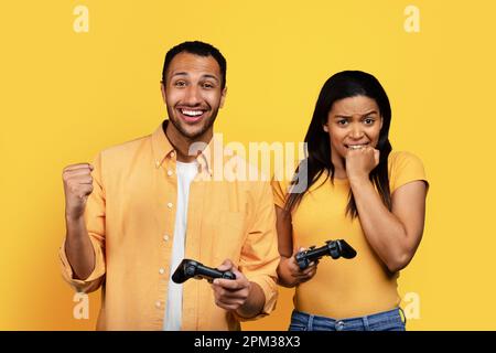 Sorridente giovane americano africano e donna triste con joystick giocare gioco online Foto Stock