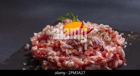 Carne macinata fatta in casa, spezie ed erbe aromatiche. Ingredienti crudi tradizionali per la cottura di cutlet o polpette. Trendy luce dura, ombra scura, pietra chiara conc Foto Stock