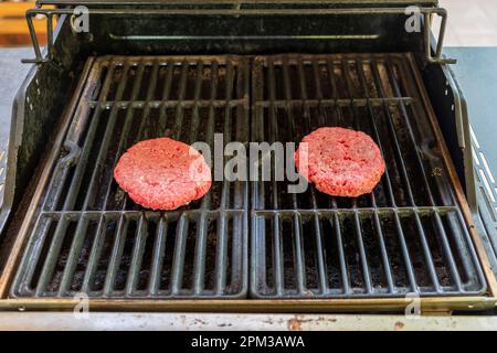 Hamburger freschi crudi su una griglia all'aperto con cucina a gas a Montgomery, Alabama, USA. Foto Stock