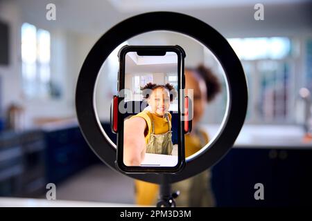 Ragazza a casa registrazione video da caricare sui social media sul telefono cellulare Foto Stock