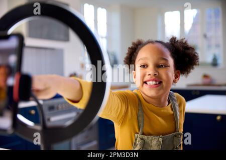 Ragazza a casa registrazione video da caricare sui social media sul telefono cellulare Foto Stock