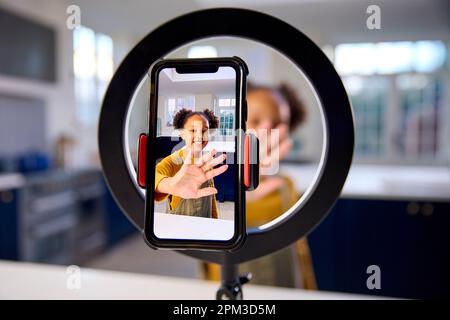 Ragazza a casa registrazione video da caricare sui social media sul telefono cellulare Foto Stock