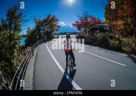 Il ciclista giapponese si ferma per scattare una foto sulle rive del lago Kawaguchi del Monte Fuji. Foto Stock