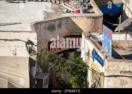 Sousse, Tunisia, 8 gennaio 2023: Vicolo tortuoso nella medina di Sousse con un segno dipinto a mano per un piccolo negozio Foto Stock