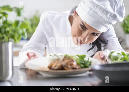 Uno chef esperto controlla il cibo finito prima che il cameriere lo porta all'ospite nel ristorante. Foto Stock